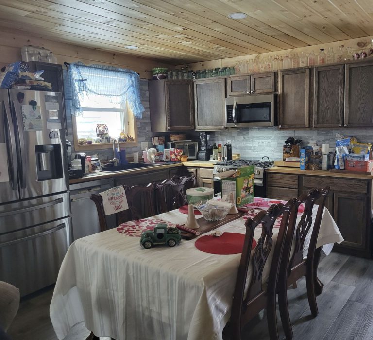 Kitchen and dining area with wooden cabinets, stainless steel appliances, and round table with white tablecloth