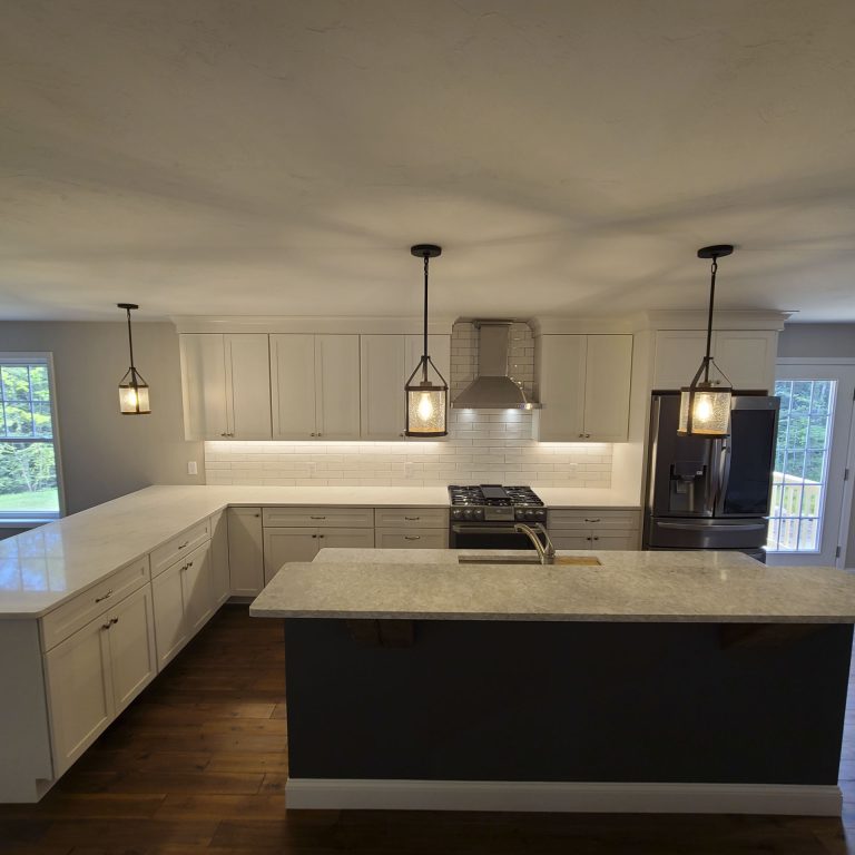 Modern kitchen with white cabinetry, black island, granite countertops, and pendant lighting